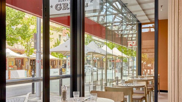 A restaurant with outdoor seating, large windows, and a view of the street. - ibis Perth (Perth)