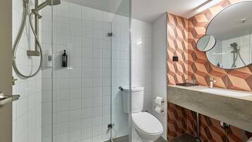 A modern bathroom with a glass-enclosed shower, a white toilet, and a vanity with a mirror.