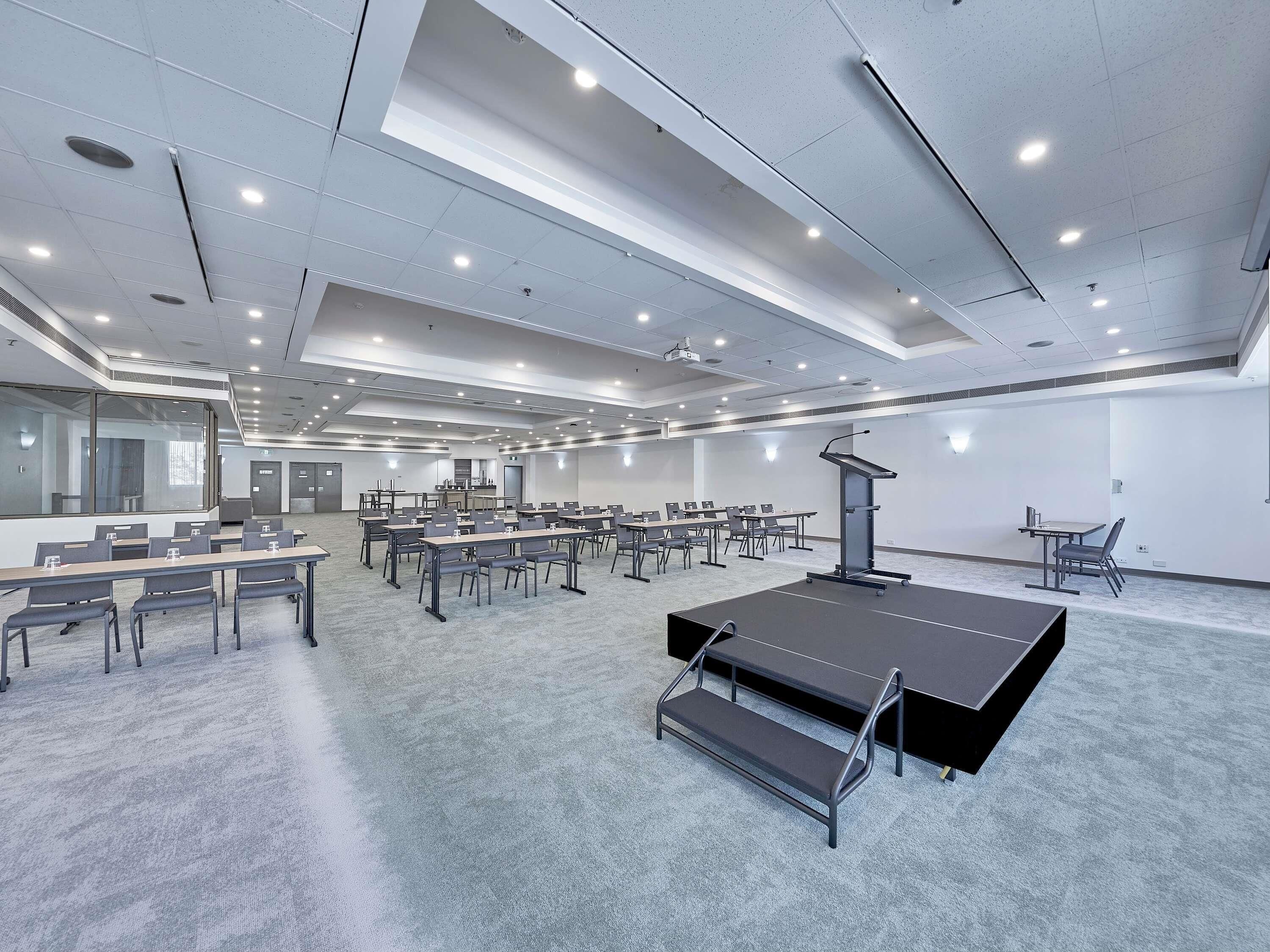 A conference room with multiple tables, a podium, and a carpeted floor.