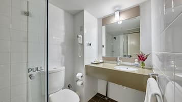 Ein modernes Badezimmer mit Duschkabine aus Glas, Toilette, Waschbecken mit Spiegel und Handtuchhalter.