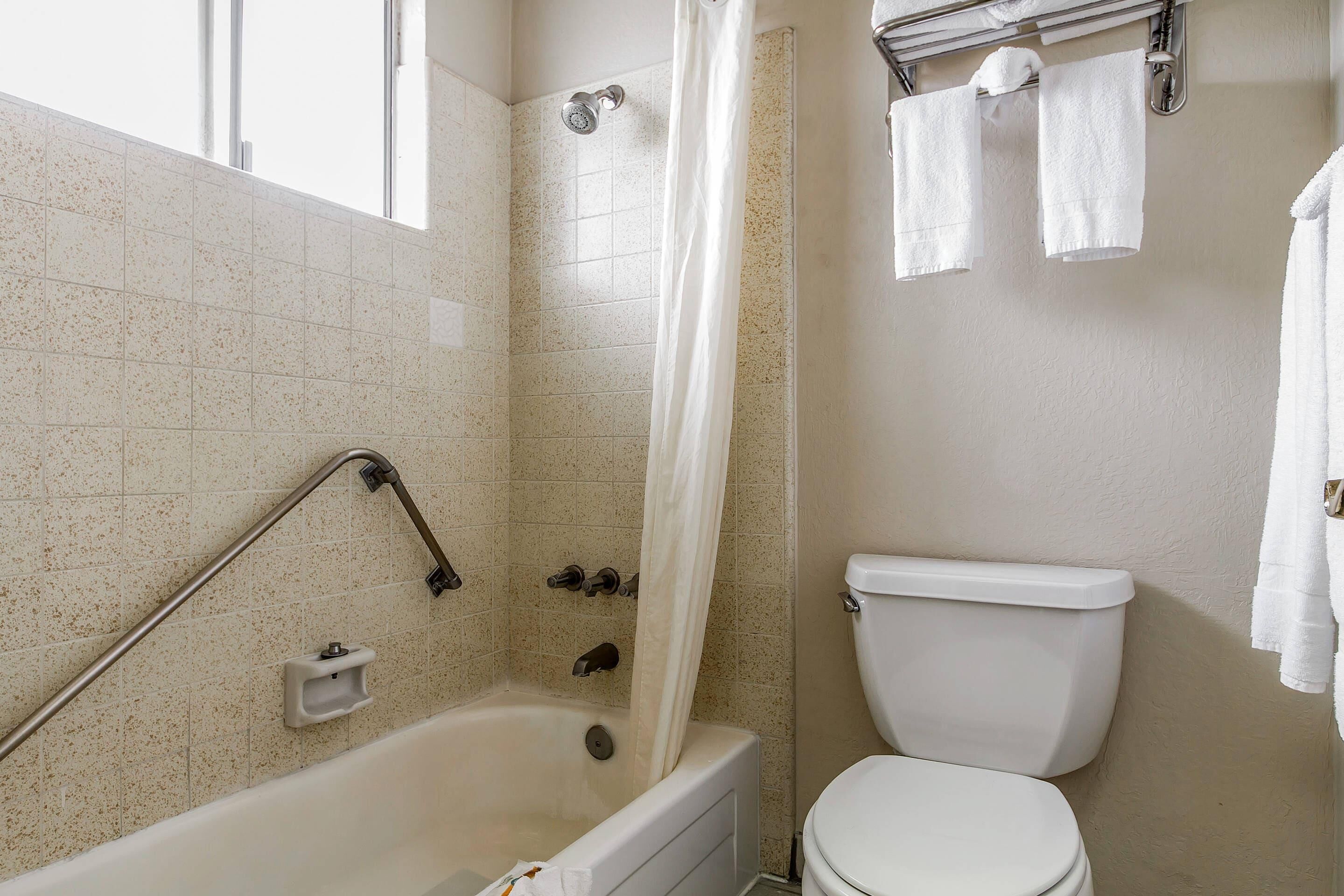 A bathroom with a bathtub, shower, and toilet.