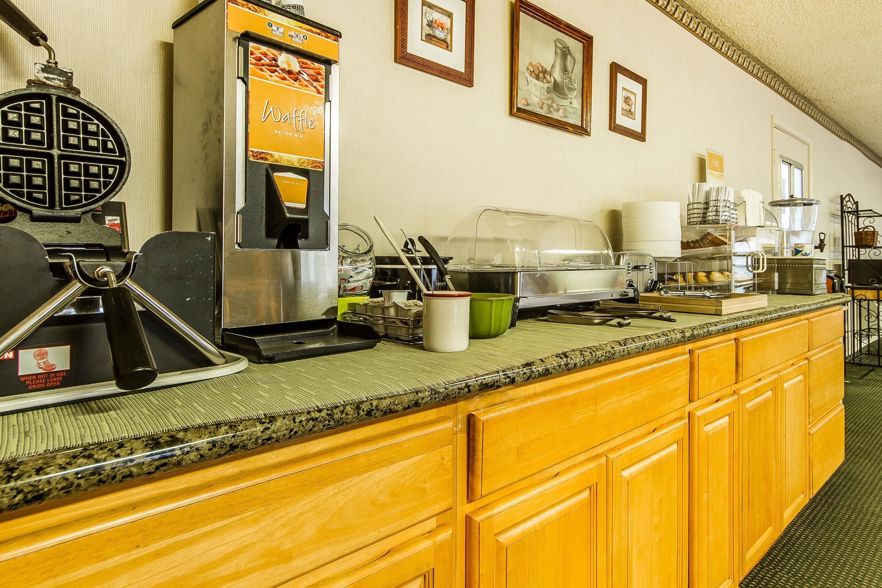 Un bar pour le petit-déjeuner équipé d’un appareil à gaufres, d’une machine à café et de différents récipients pour aliments.