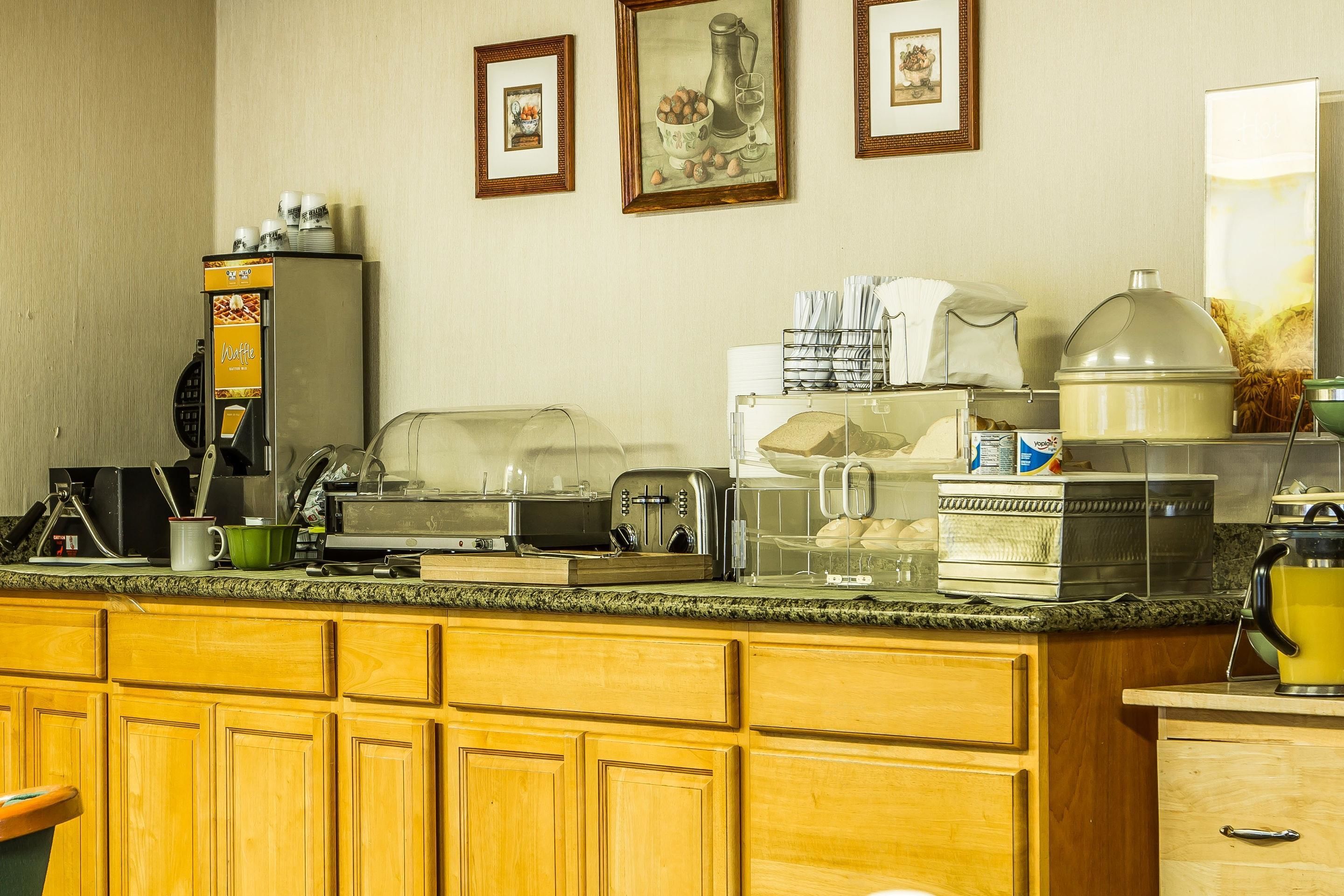 A hotel kitchen with a buffet setup, including a coffee machine, toaster, and various food containers.