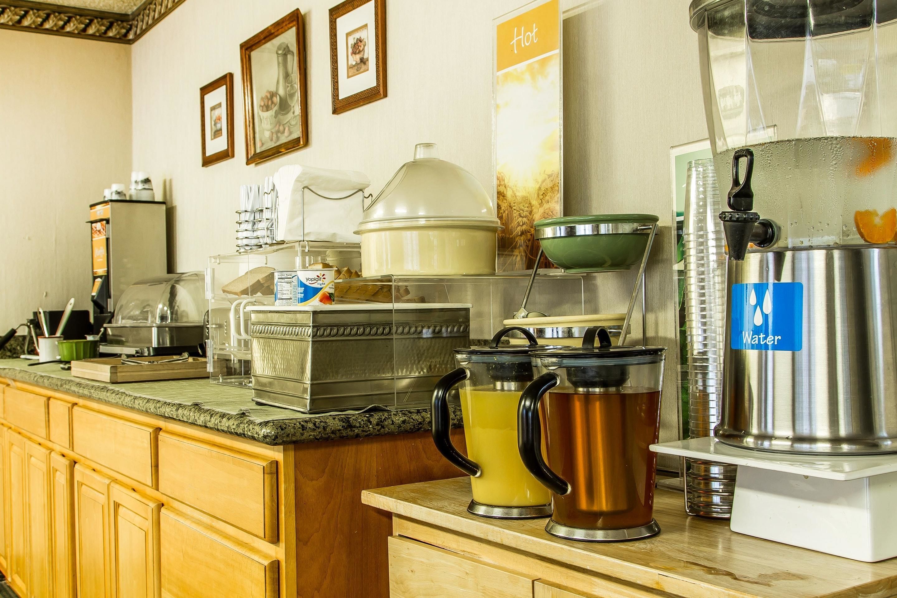A kitchen counter with various appliances and containers, including a coffee maker, a water dispenser, and several pots and pans.