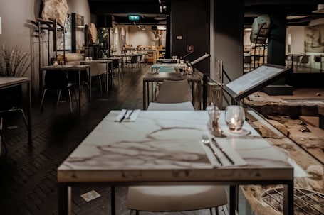 A restaurant with a long table set for dining, chairs, and a menu stand.