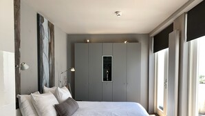 A bedroom with a large bed, grey wardrobe, and a view through the window. - Derlon Hotel Maastricht (Maastricht)