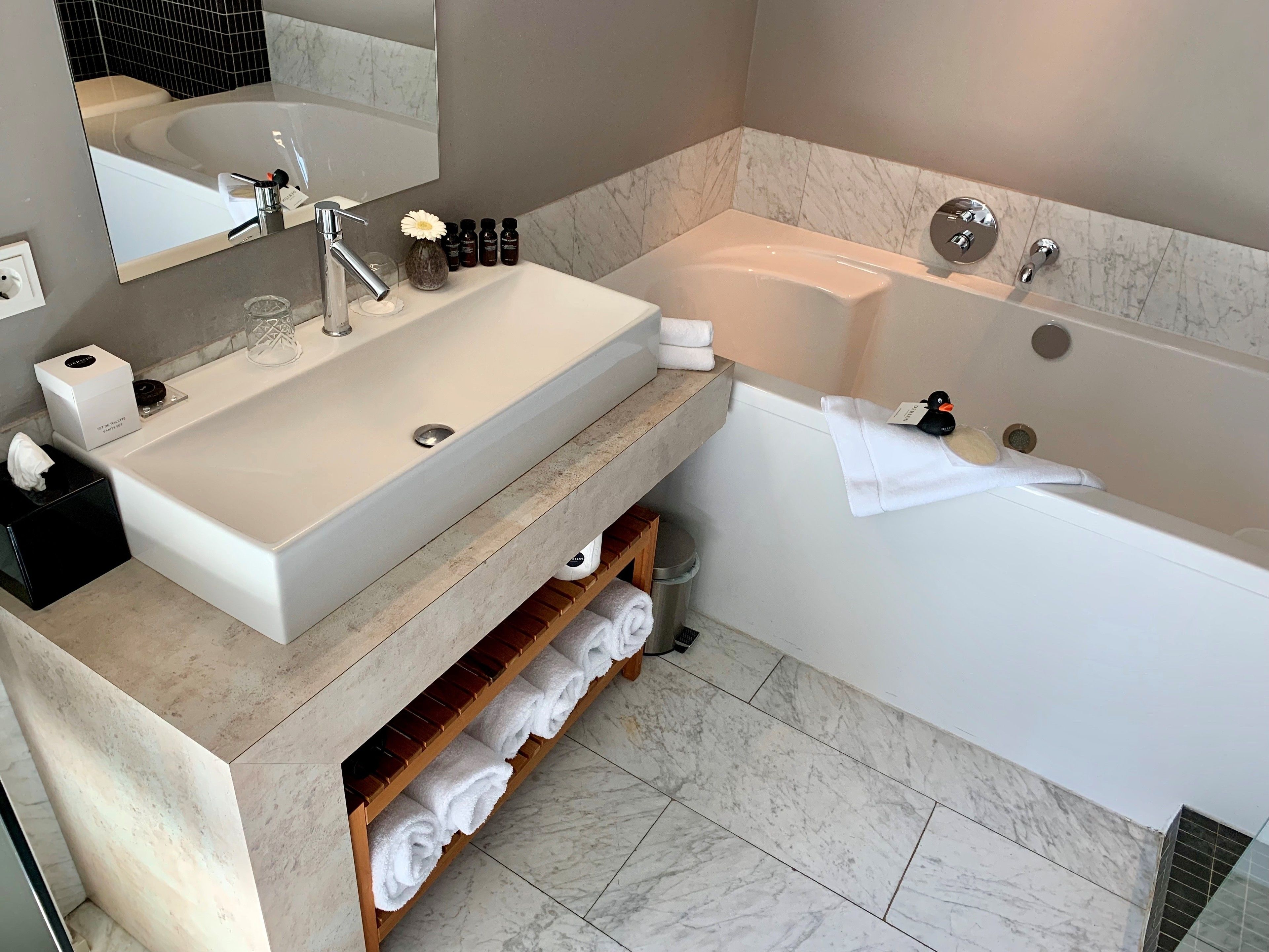 Une salle de bain moderne dotée d’un grand lavabo, d’une baignoire et d’un meuble-lavabo avec des étagères pour les serviettes.
