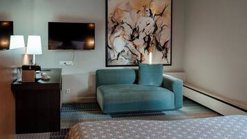 Hotelkamer met een bed, een bureau met een lamp, een televisie en een groot abstract schilderij.