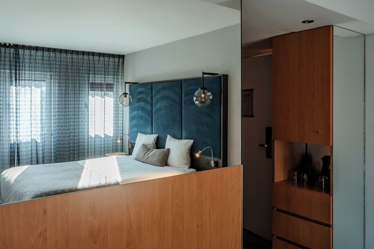 Ein modernes Schlafzimmer mit einem Bett, Vorhängen, einem Kopfteil und einem Holzkasten.
