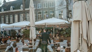 An outdoor café with wicker chairs and white umbrellas, set against a backdrop of traditional buildings. - Derlon Hotel Maastricht (Maastricht)