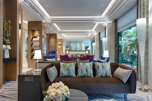 A modern lobby with a brown sofa, a glass coffee table, and a bouquet of flowers.