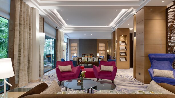 A spacious lobby with a modern design, featuring a central seating area with two sofas and a coffee table, a fireplace, and a bookshelf. - Hôtel Garden Elysées (Paris)