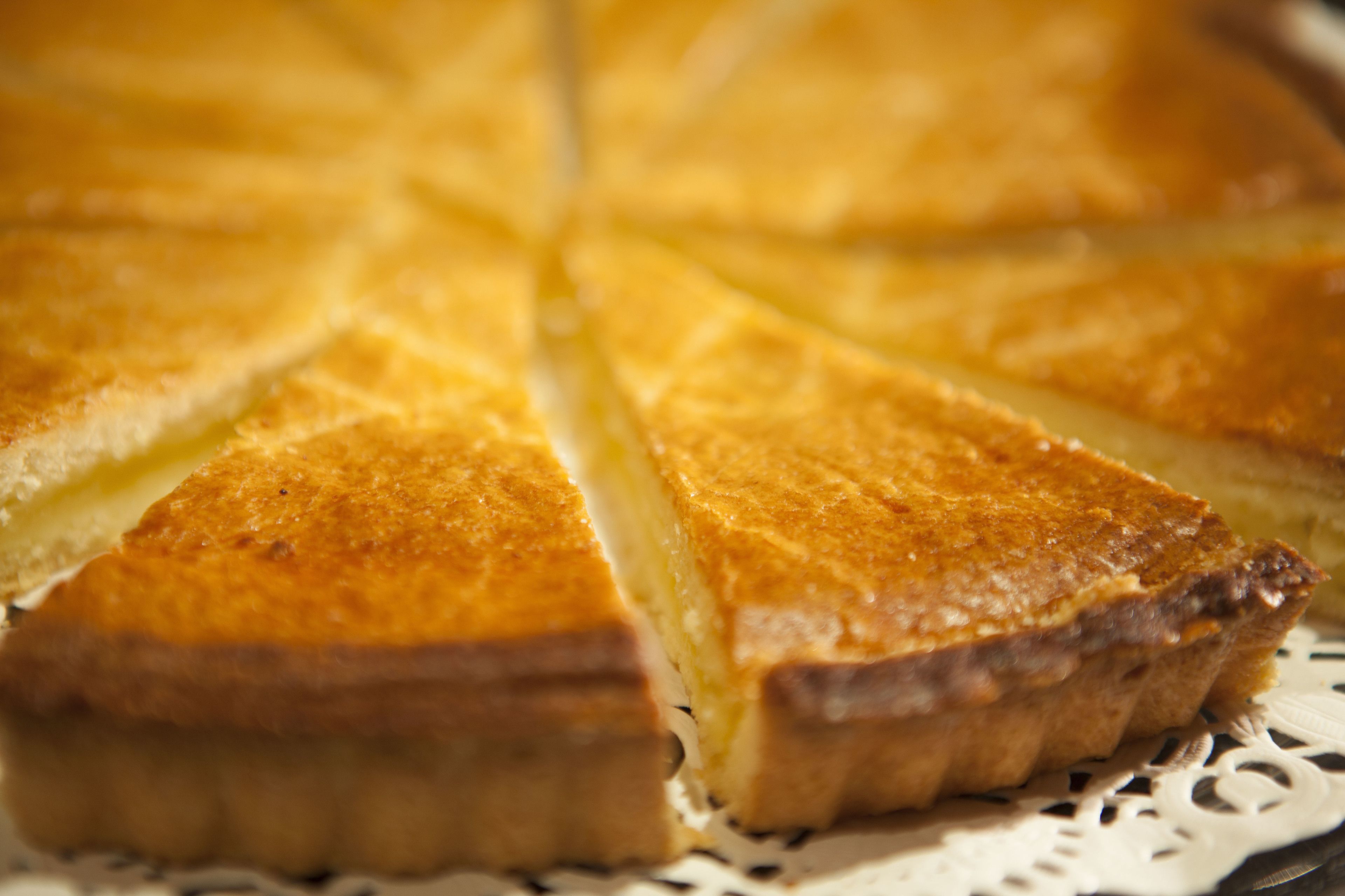 A close-up of a pie with a golden-brown crust, sliced into triangular pieces.