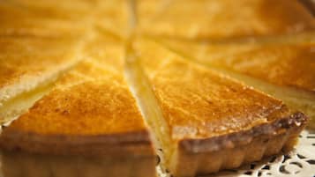 A close-up of a pie with a golden-brown crust, sliced into triangular pieces.