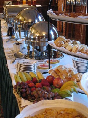 A buffet table with various food items including fruits, pastries, and dishes.
