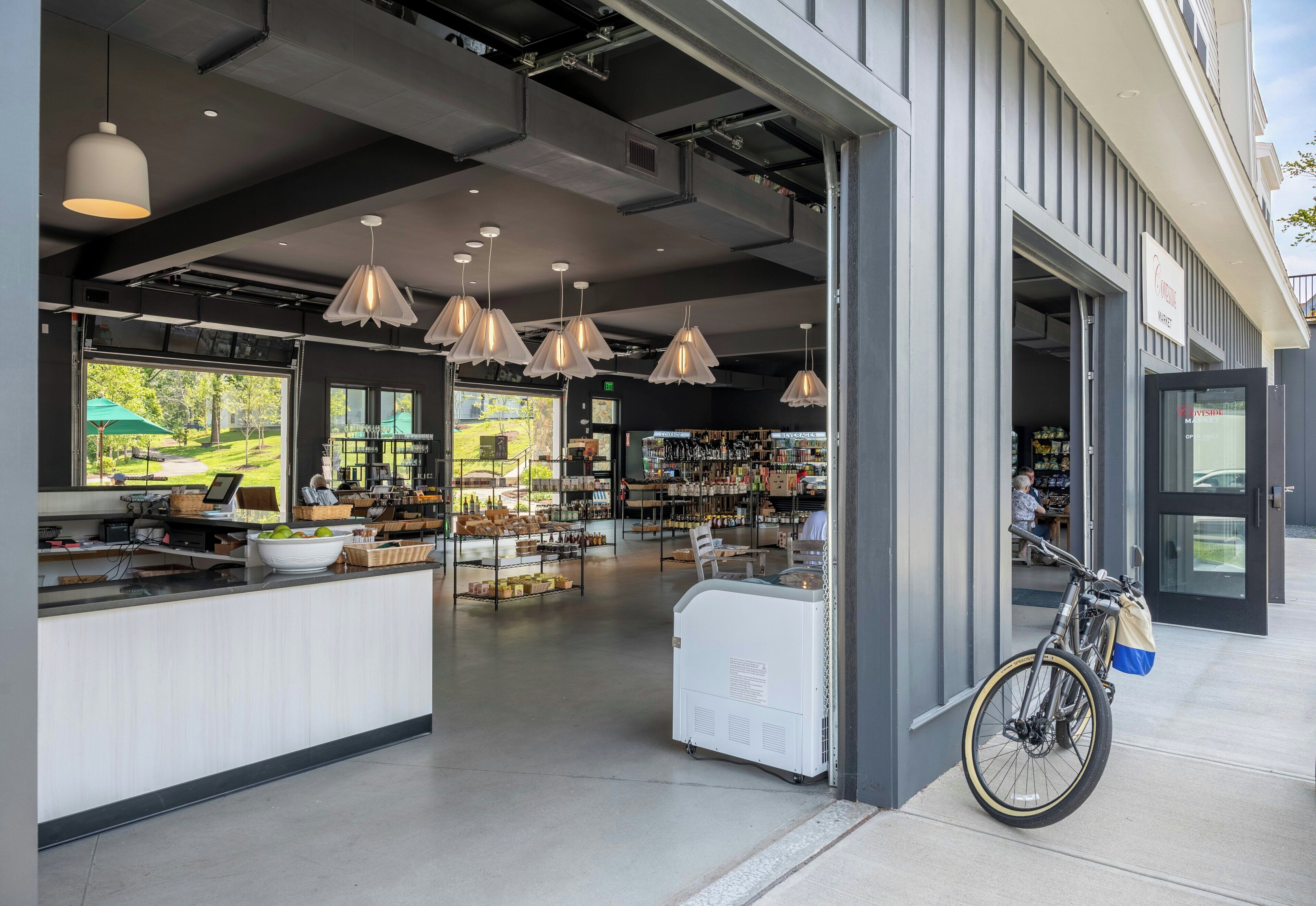 A cafe with a counter, hanging pendant lights, and a bicycle parked outside.