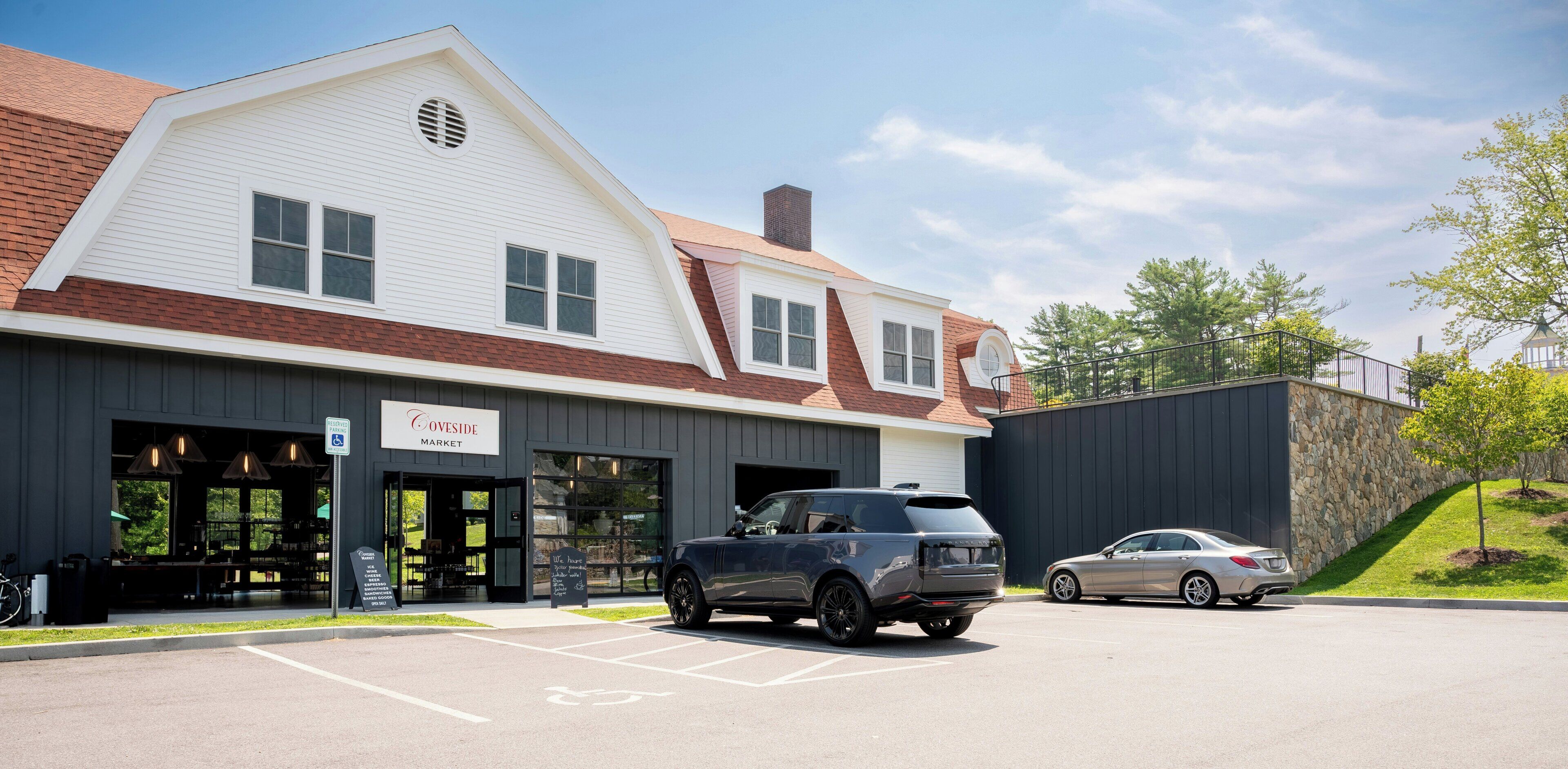 Un bâtiment sur lequel on peut lire l’inscription « Coveside Market », et un espace de stationnement où sont garées deux voitures.