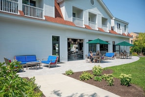 A building with a covered patio area featuring outdoor seating and umbrellas.