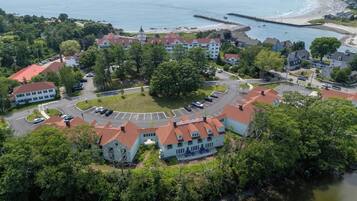 An aerial view of a coastal town with a central roundabout, buildings with red roofs, and a beach in the background.
