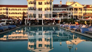 A hotel with a large pool, outdoor seating, and a prominent building with a balcony. - The Colony Hotel (Kennebunkport)