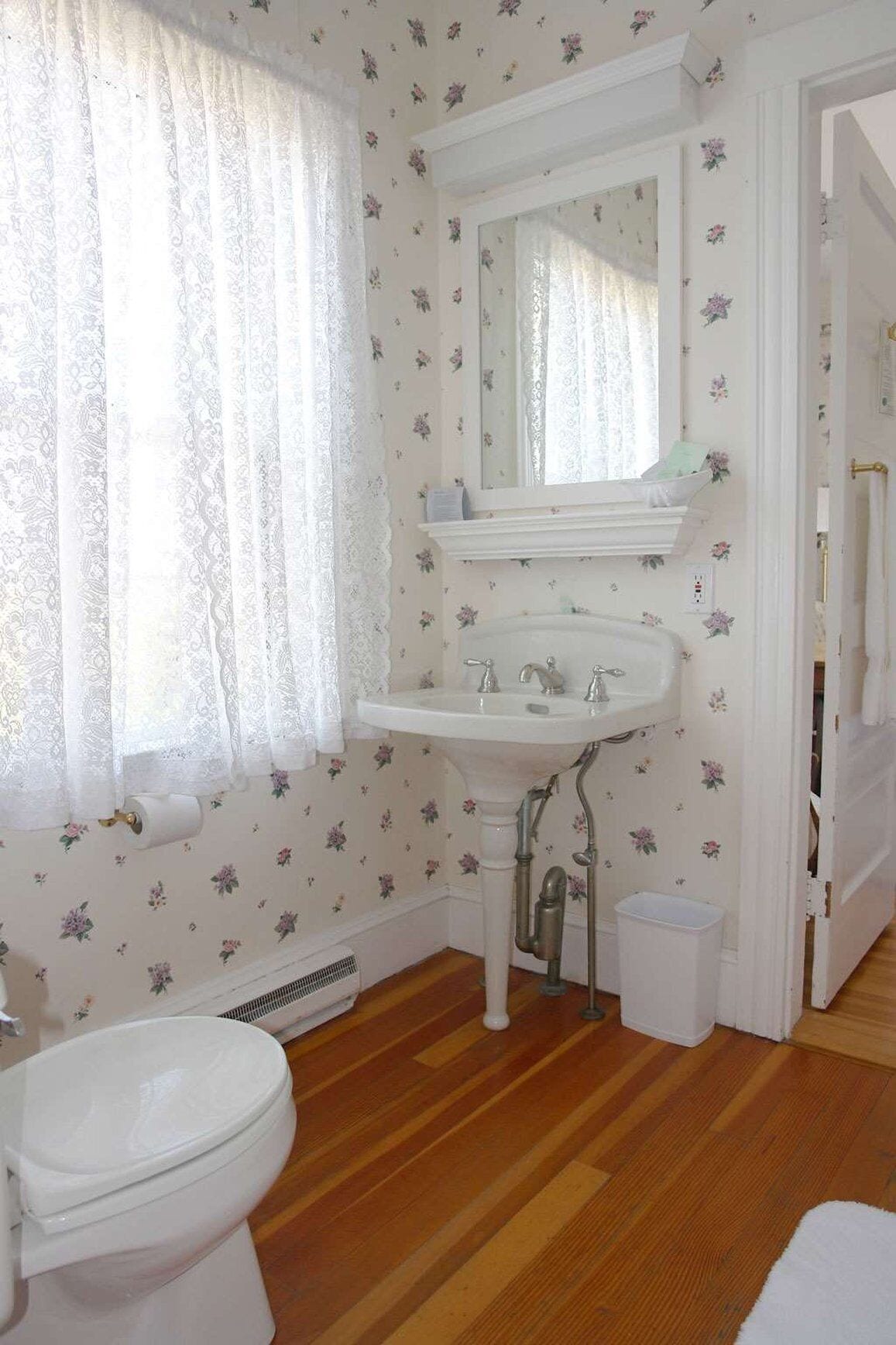Ein Badezimmer mit weißem Waschbecken, Spiegel und Toilette.