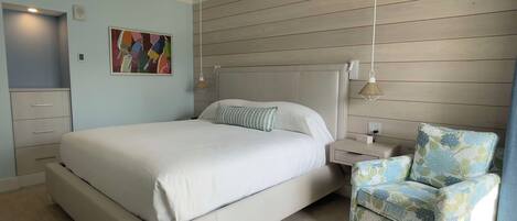 A bedroom with a bed, bedside tables, a chair, and a wall-mounted artwork.