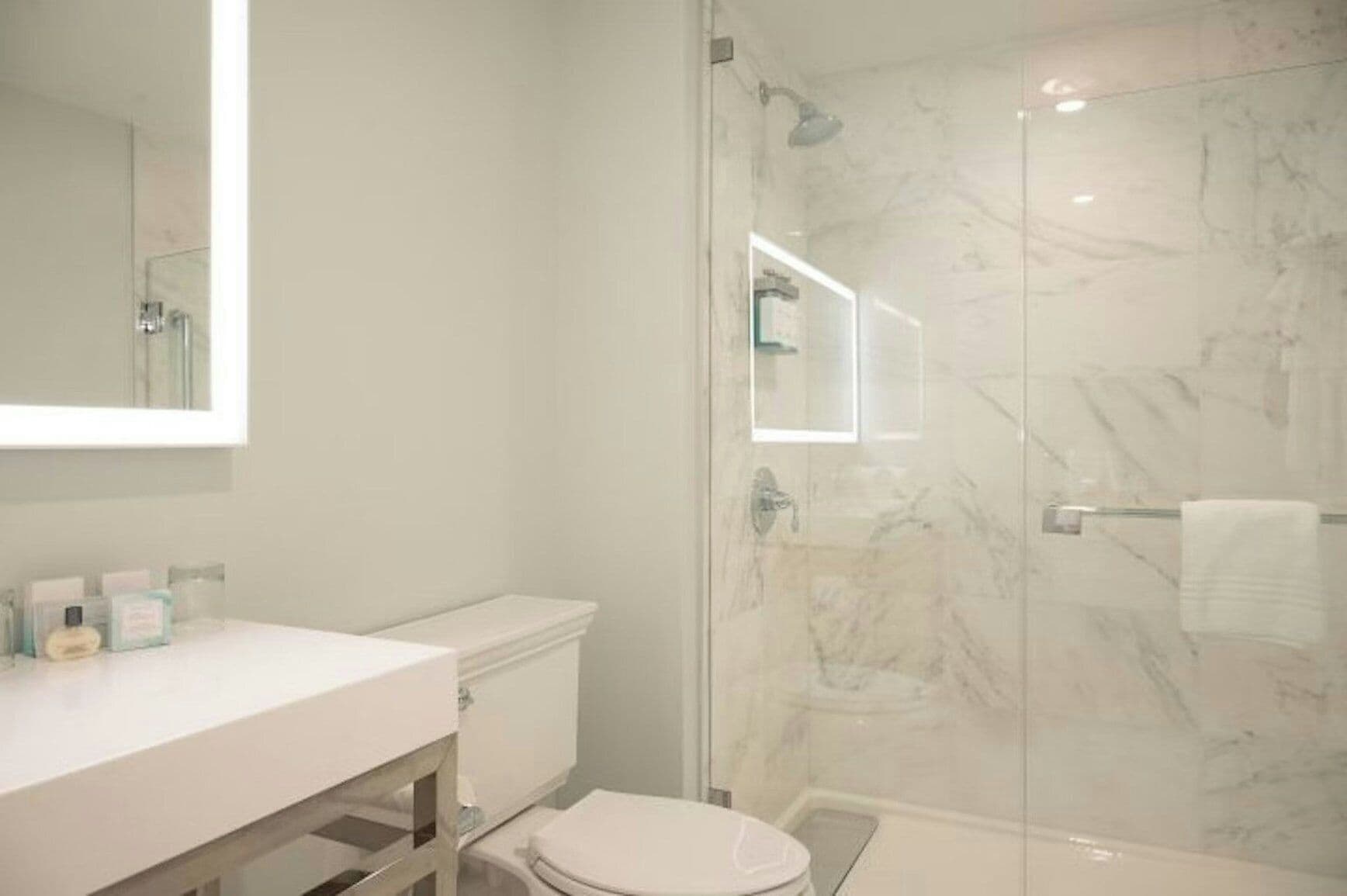Un bagno moderno con cabina doccia in vetro, un water bianco e un mobile lavabo con articoli da toilette.