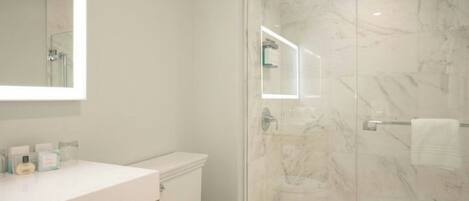 Un bagno moderno con cabina doccia in vetro, un water bianco e un mobile lavabo con articoli da toilette.