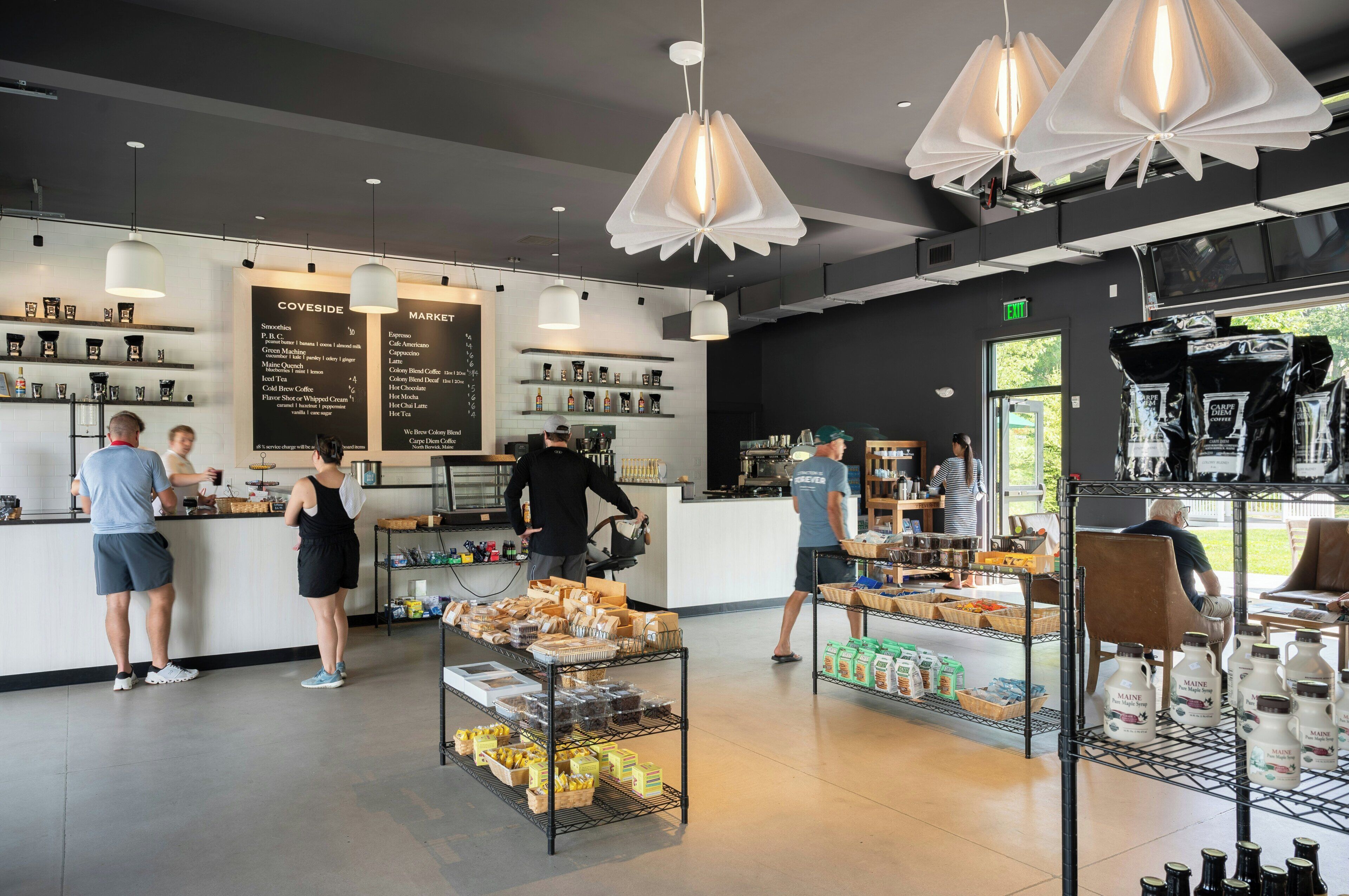 L’intérieur d’un café, avec un tableau affichant le menu, des machines à café et une vitrine présentant les différents plats proposés.
