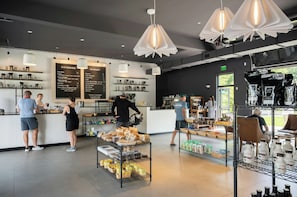 A cafe interior with a menu board, coffee machines, and a display of food items. - The Colony Hotel (Kennebunkport)
