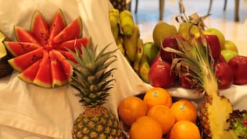 Ein Tisch mit einer Auswahl an Früchten, darunter Wassermelone, Ananas, Orangen und Äpfel.