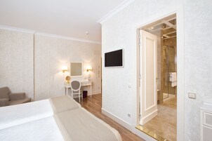 Ein Hotelzimmer mit Bett, Schreibtisch mit Stuhl, Fernseher und Duschbereich.