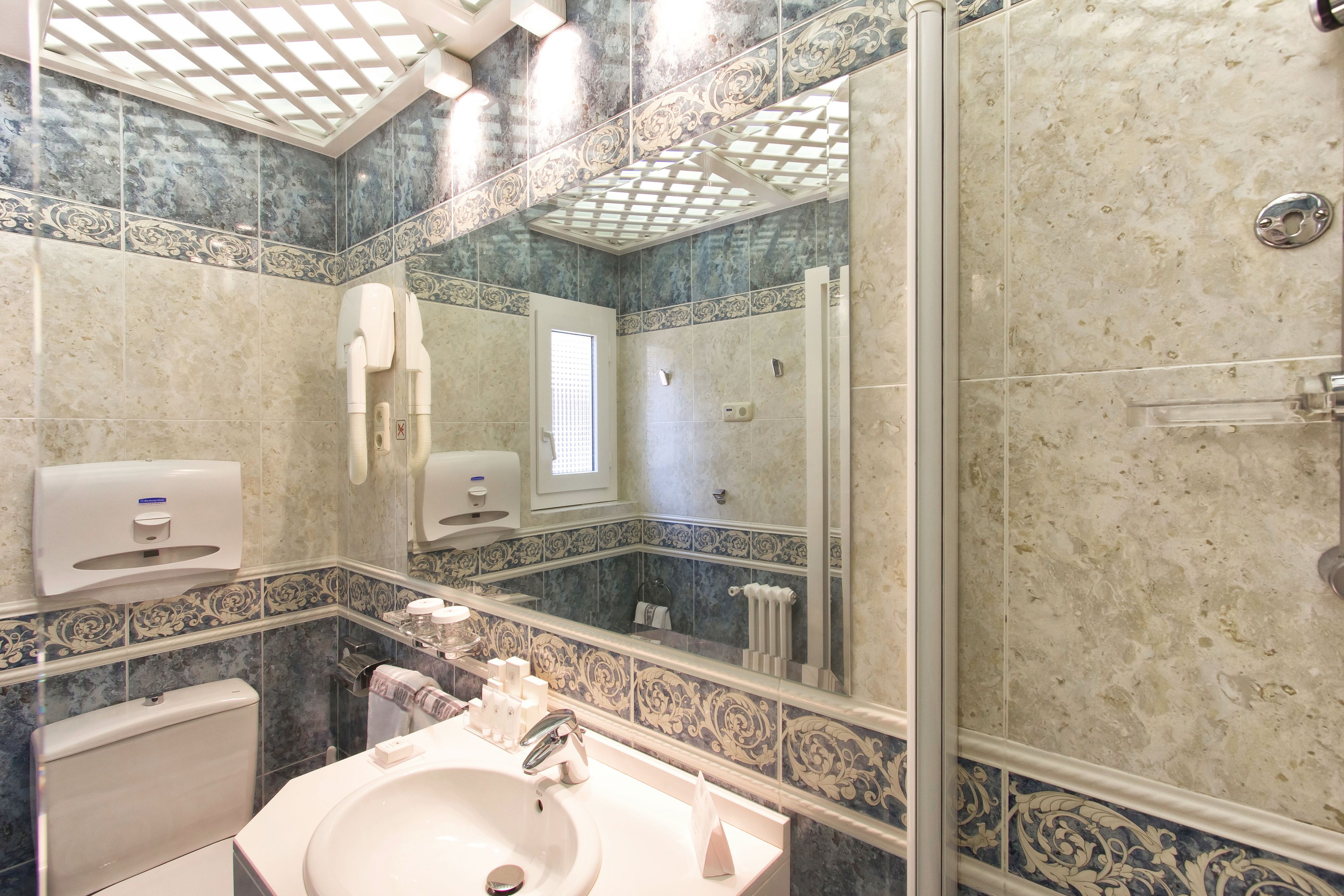 A bathroom with a sink, mirror, and shower.