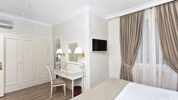 Una camera d'albergo con un letto, una toeletta con specchio, una scrivania e una televisione.