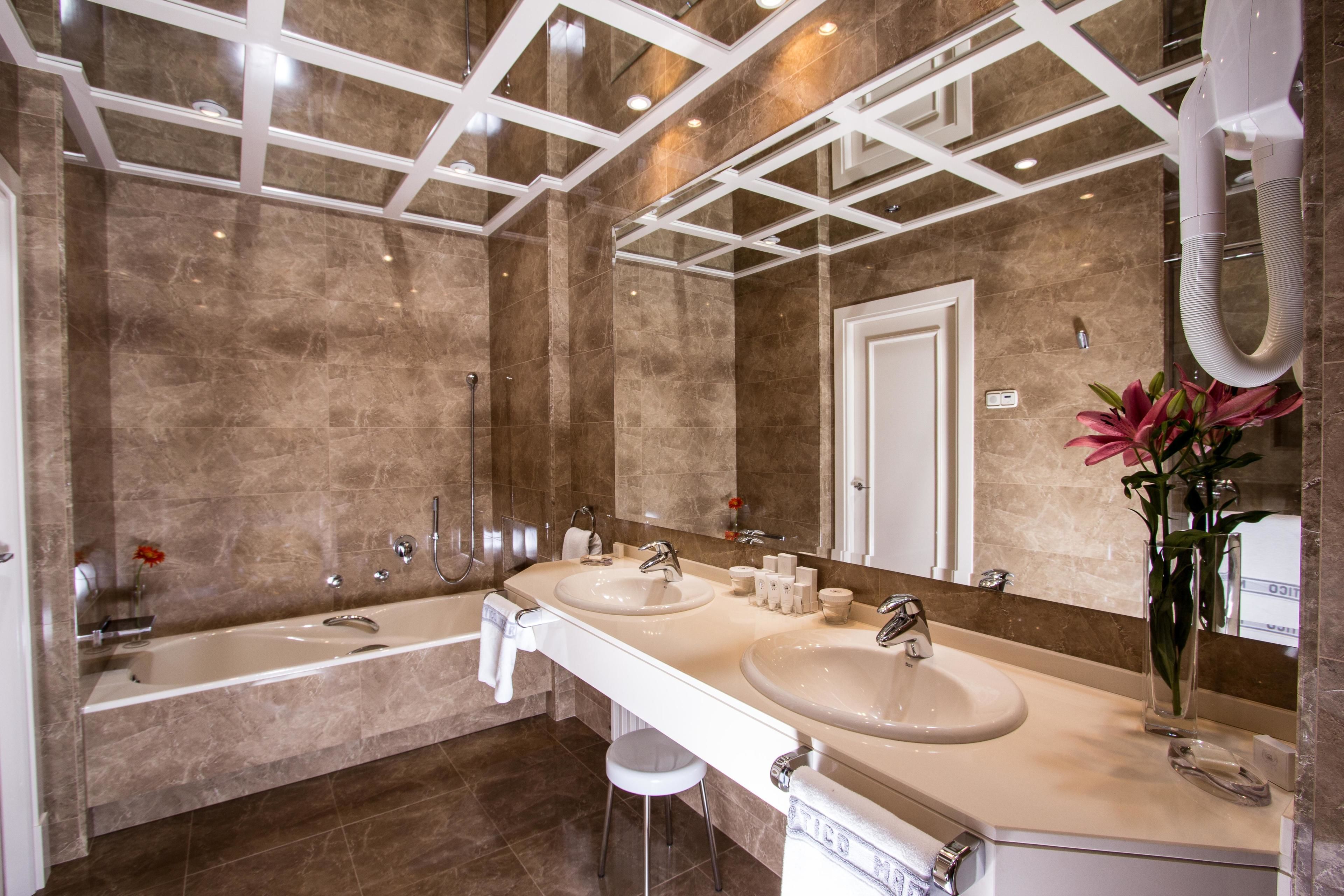 A modern bathroom with two sinks, a large bathtub, and a mirror.