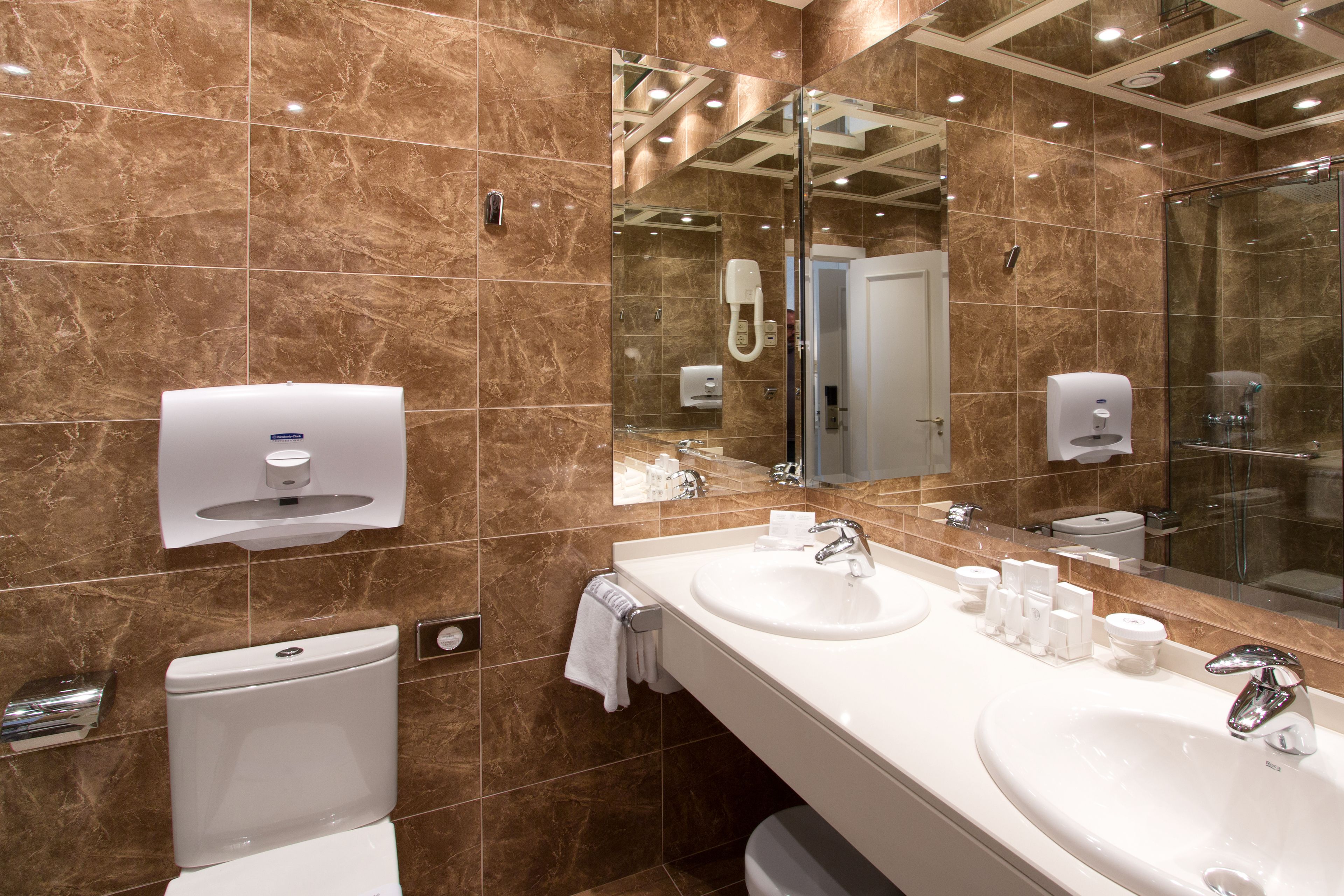 Un baño moderno con dos lavamanos, un inodoro y una cabina de ducha de vidrio.