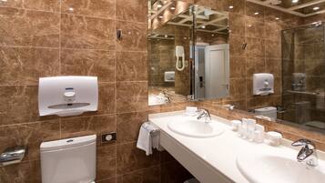 Un baño moderno con dos lavamanos, un inodoro y una cabina de ducha de vidrio.
