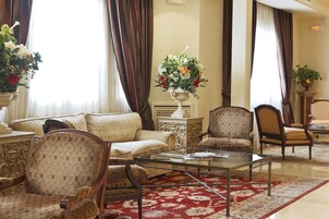 A living room with a sofa, chairs, a coffee table, and a floral arrangement.