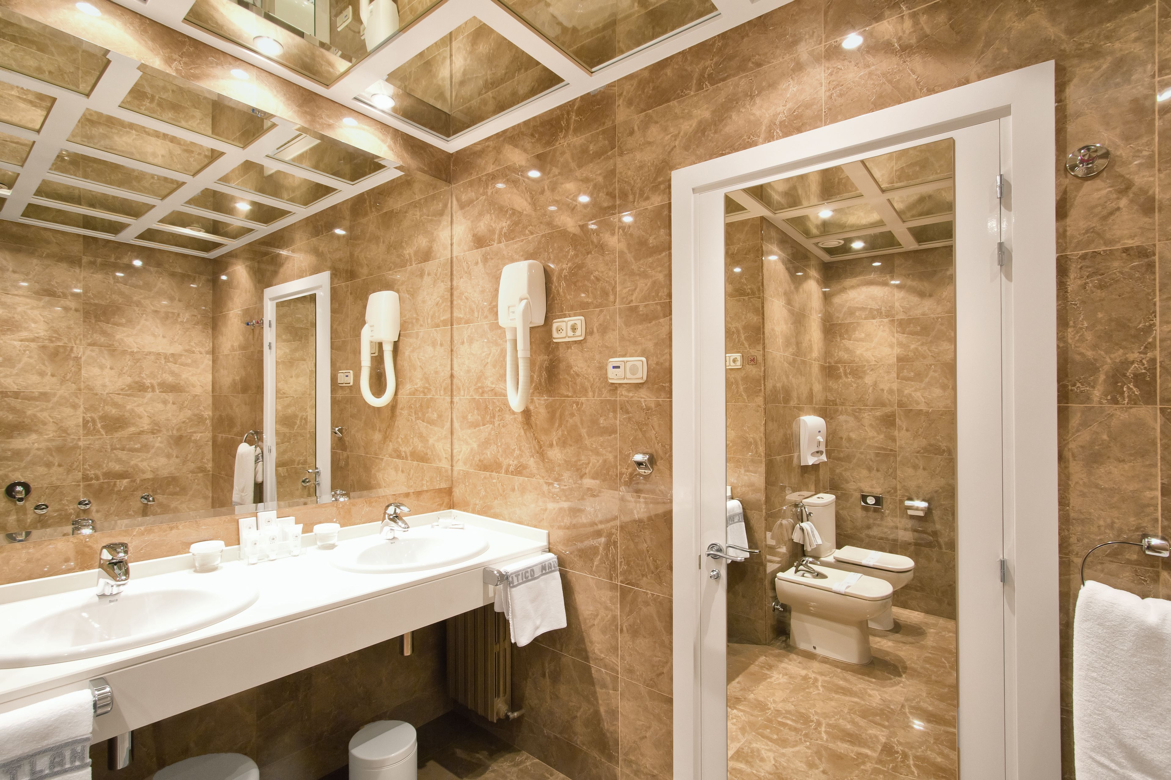 Un baño moderno con dos lavamanos, un espejo, una ducha e inodoro.