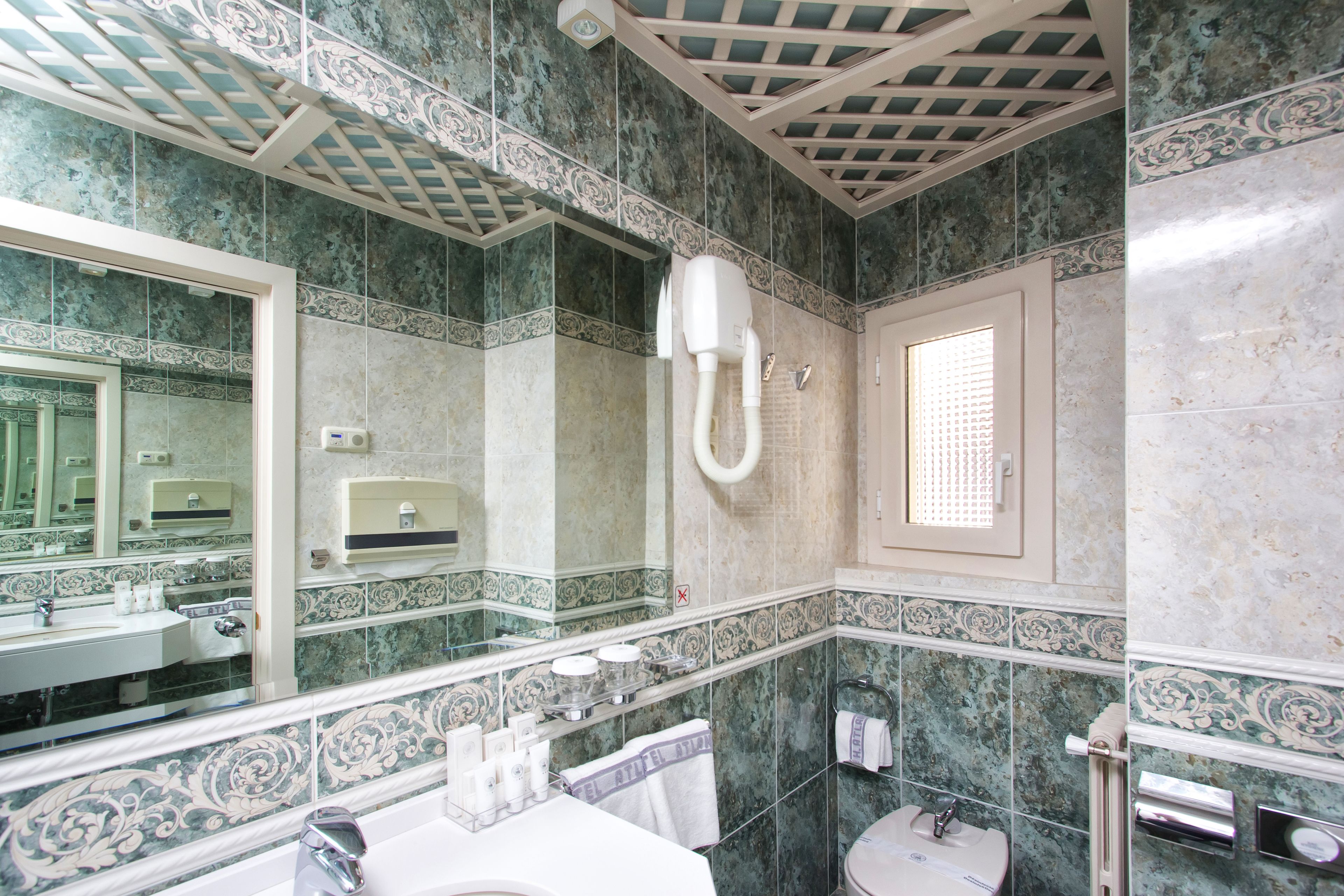 Un baño con un espejo grande, un lavamanos, un inodoro y una ducha.