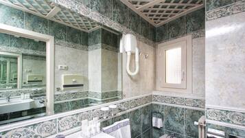Un baño con un espejo grande, un lavamanos, un inodoro y una ducha.