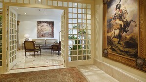 A grand hallway with a large ornate painting, a sofa set, and a decorative gate.