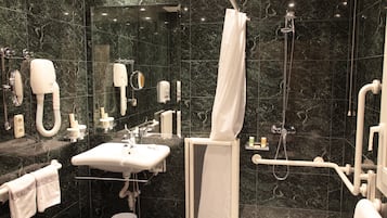 A modern bathroom with a sink, mirror, towel rack, shower, and hand dryer.