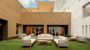 An outdoor seating area with sofas and tables, string lights, and a green artificial turf.