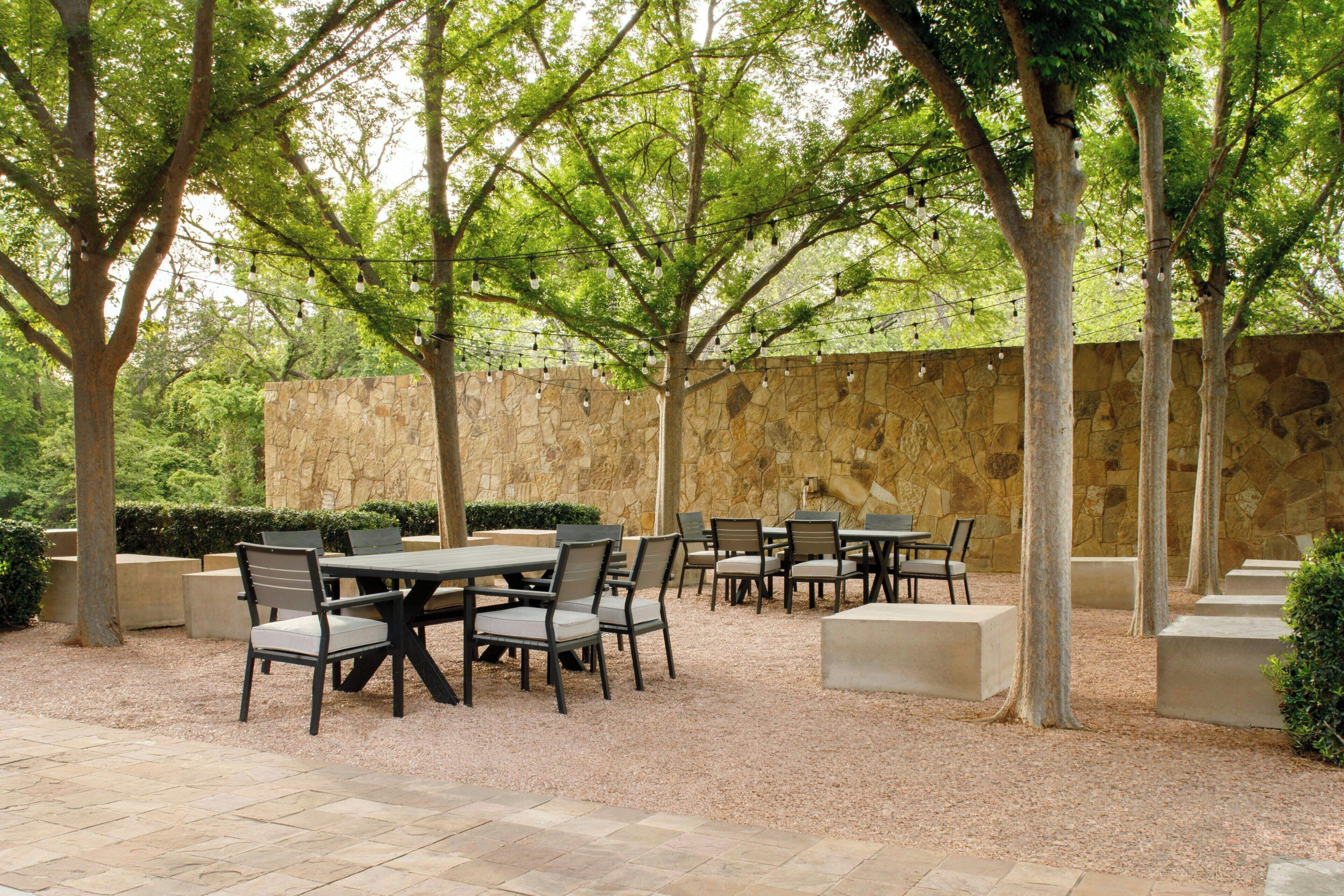 An outdoor patio with stone walls, tables, and chairs.