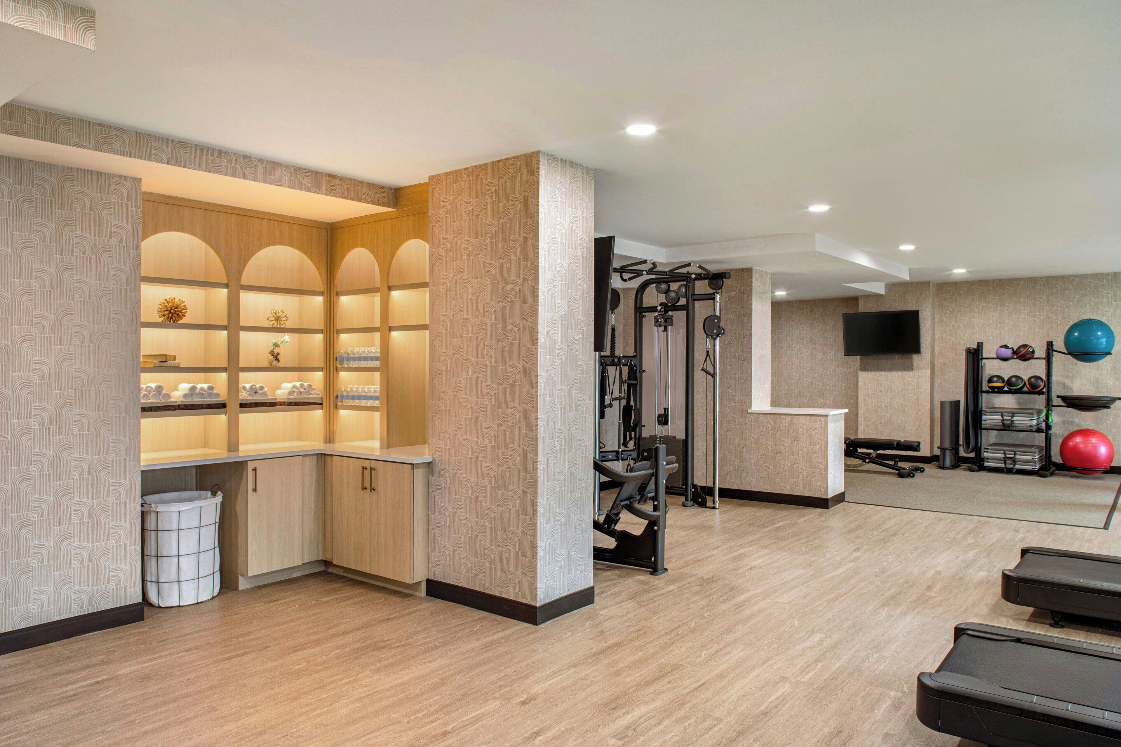 Un gimnasio con equipo de ejercicio, un televisor y una pared con estanterías.