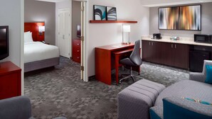 Habitación de hotel con cama, escritorio, kitchenette y televisor.