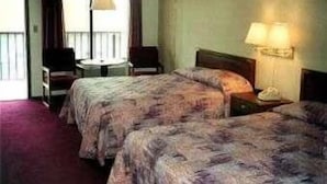 A hotel room with two beds, a small table, a chair, and a window with curtains. - Twinkle Inn (Branson)