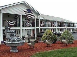A motel with a two-story structure, a flag, and a fountain in the front yard. - Twinkle Inn (Branson)
