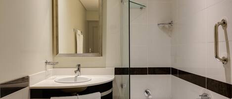 A modern bathroom with a glass-enclosed shower, a sink with a mirror above it, and a bathtub.